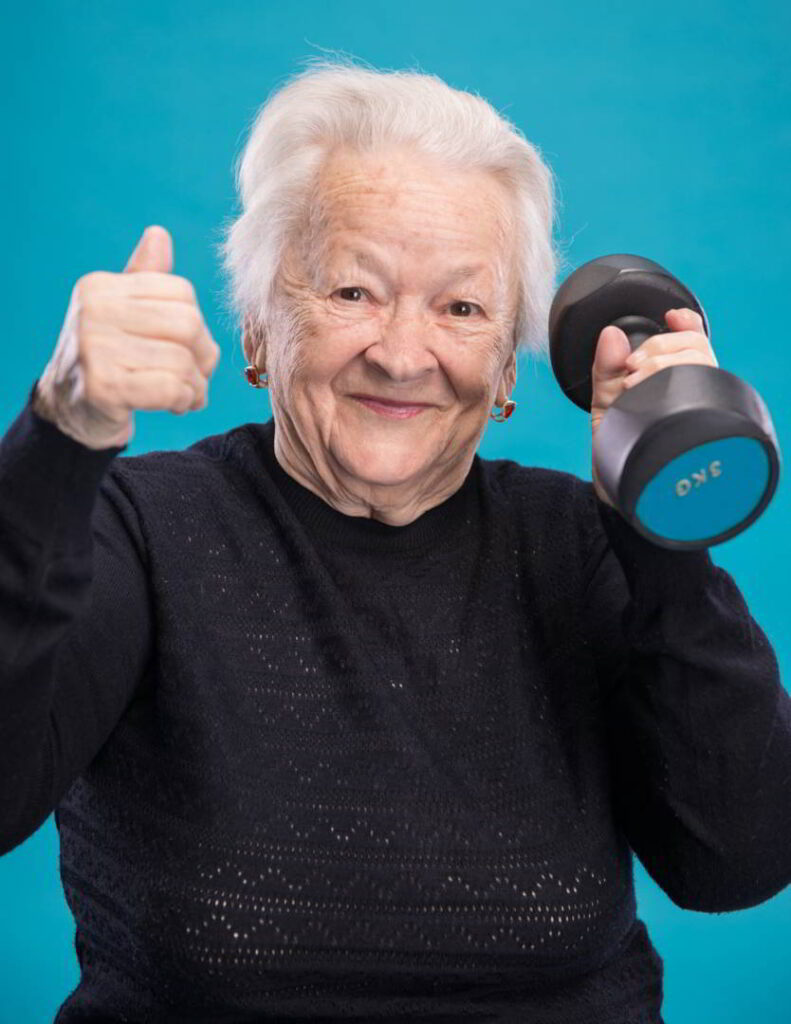 Elderly woman holding a small barbell and giving the thumbs up hand signal